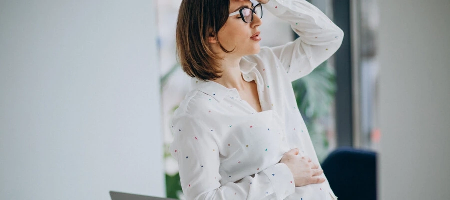 mulher grávida no trabalho sentindo dor de cabeça 